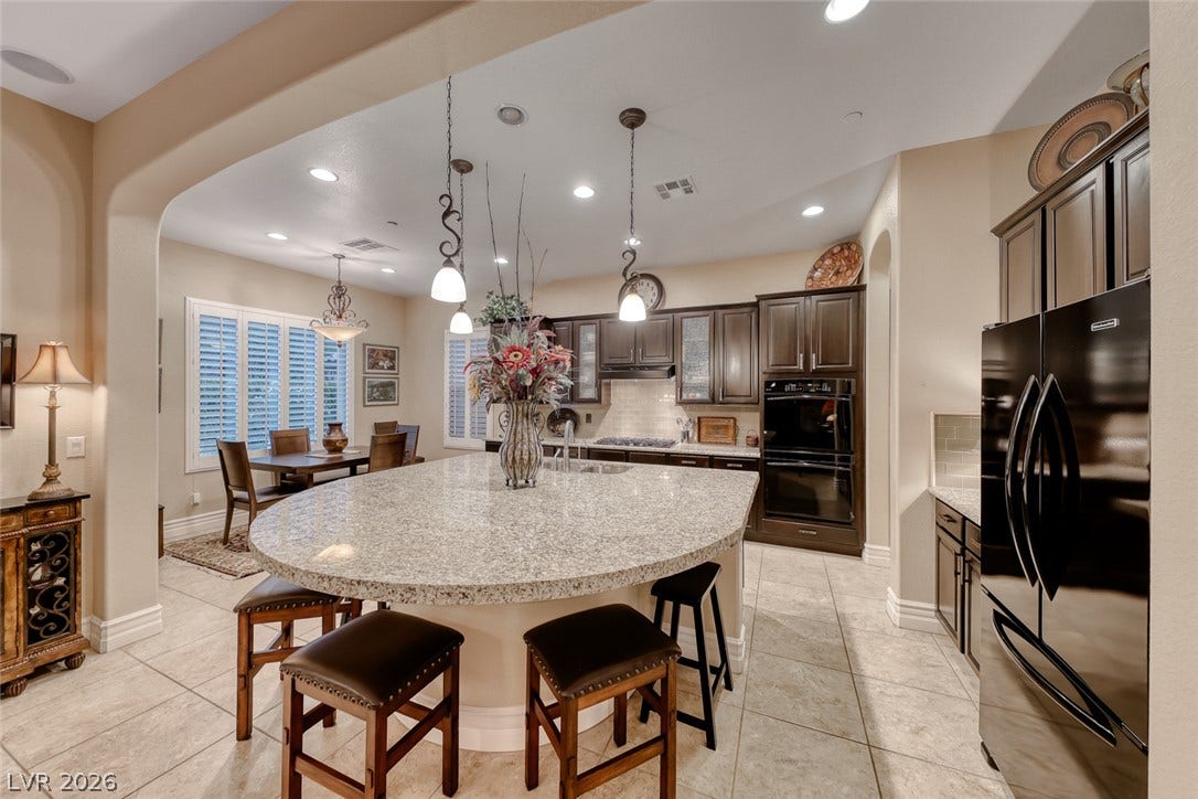 41 Moltrasio Lane, Henderson, NV 89011 Gleaming stone countertops and dark cabinetry define this expansive culinary space.