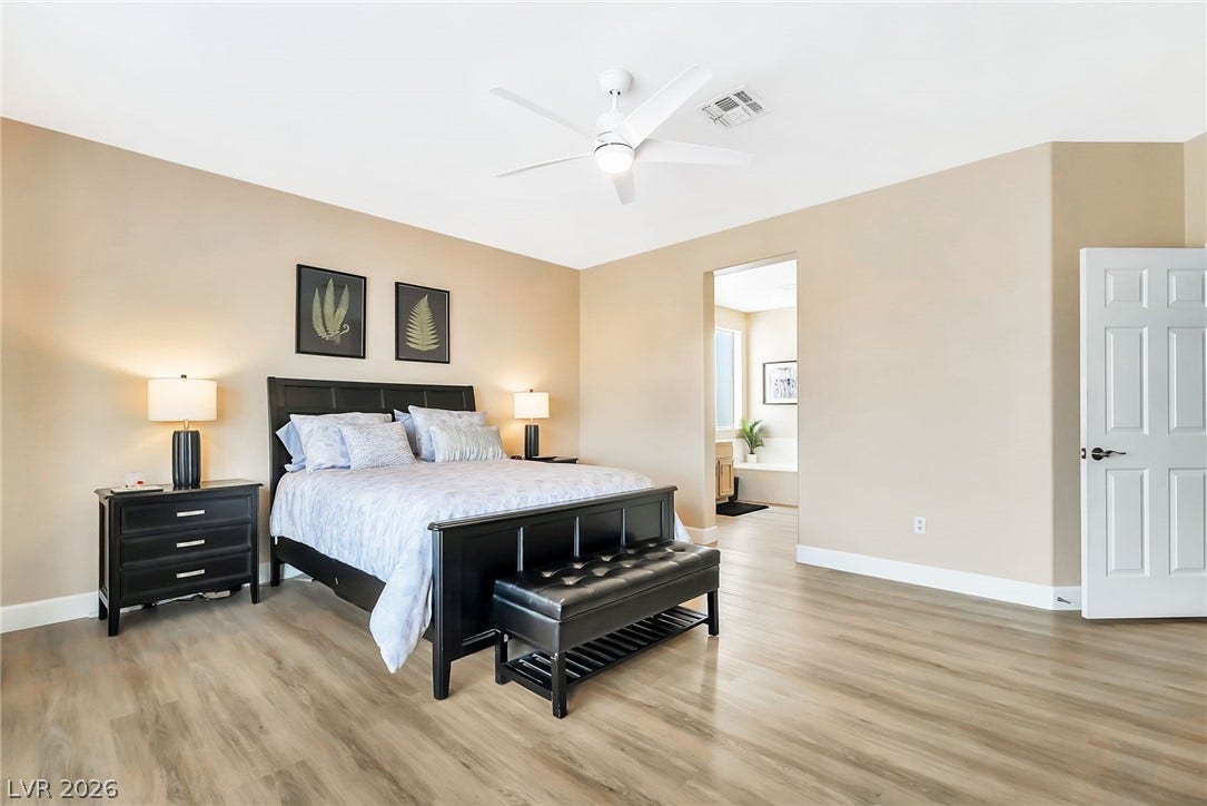 Smooth wood-look flooring and clean lines define this inviting primary bedroom suite.