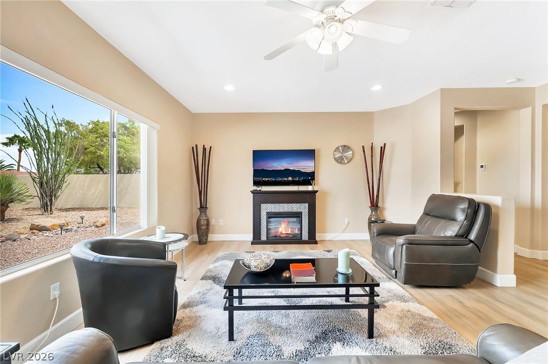 A classic fireplace and large picture window elevate this comfortable living room space.