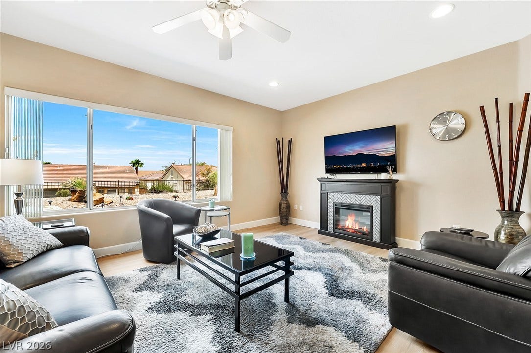 Sunlight streams through a large picture window into this comfortable living room with a fireplace.