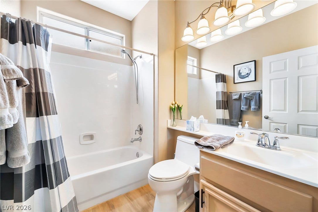 A well-designed bathroom features a built-in tub and light wood flooring.