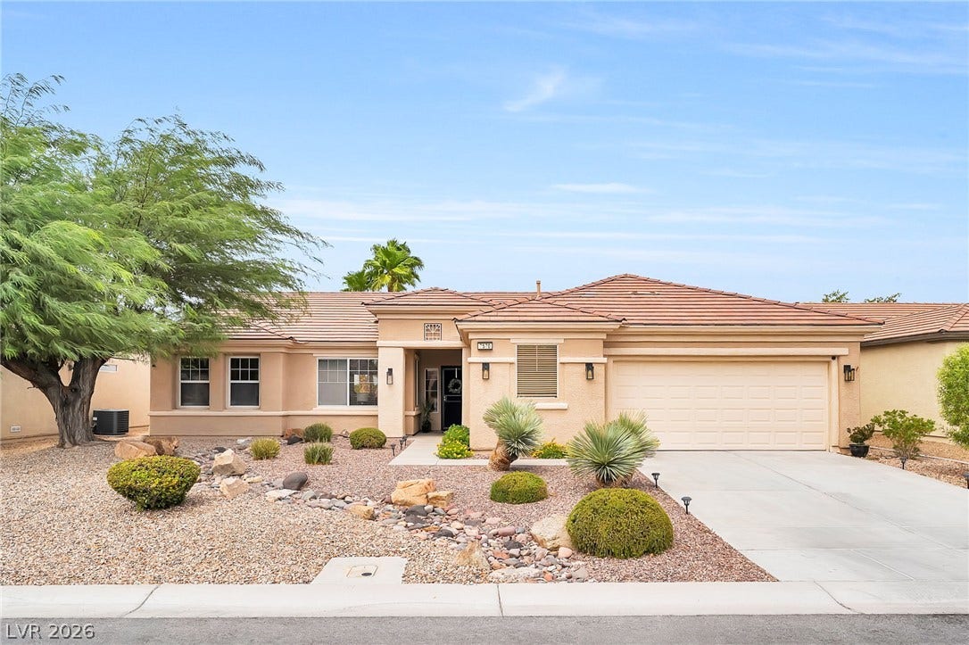 Desert-inspired landscaping welcomes visitors to this elegant single-level home featuring a tile roof.