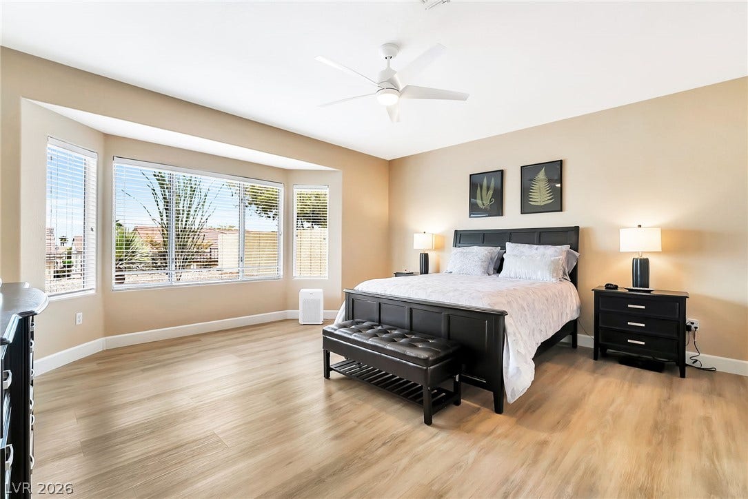 Generous windows fill this spacious bedroom with natural light highlighting the smooth wood-look flooring.