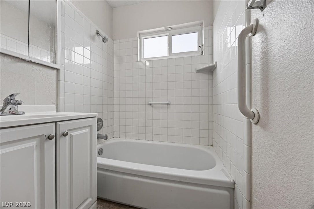 120 W Victory Road, Henderson, NV 89015 Classic white wall tiles surround a built-in bathtub paired with a matching vanity.