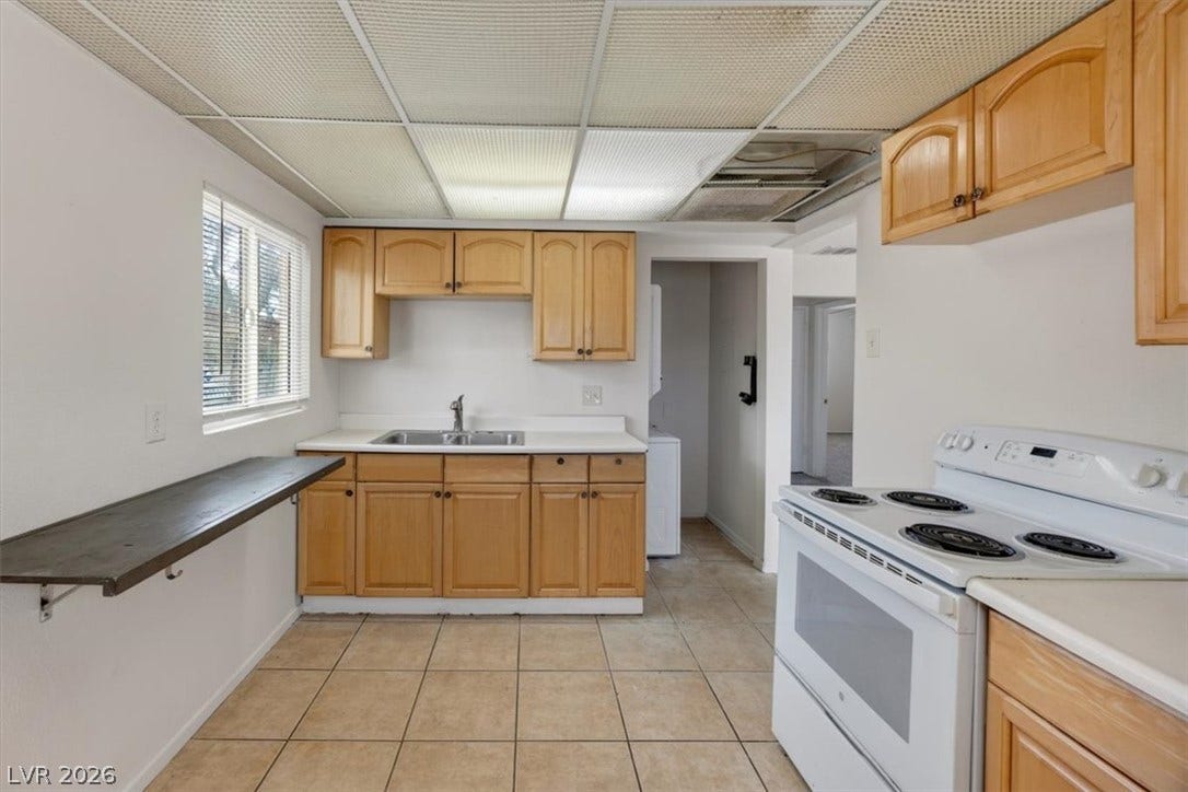 120 W Victory Road, Henderson, NV 89015 Classic wooden cabinetry and neutral tiled flooring maximize storage and utility in this kitchen layout.