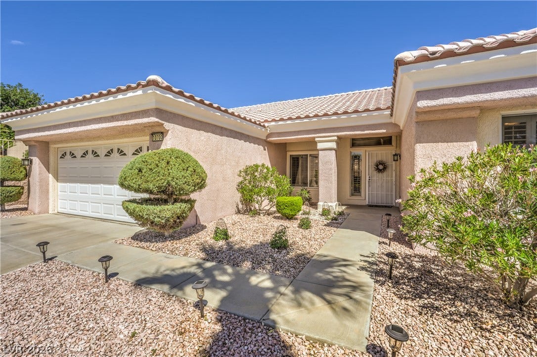 10700 Grand Cypress Avenue, Las Vegas, NV 89134 A concrete walkway leads past desert landscaping to the welcoming covered entrance of this tile-roofed home.