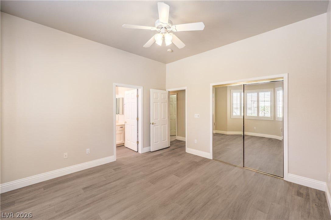 10700 Grand Cypress Avenue, Las Vegas, NV 89134 Smooth wood-look flooring and soaring ceilings define this airy bedroom with mirrored closets.