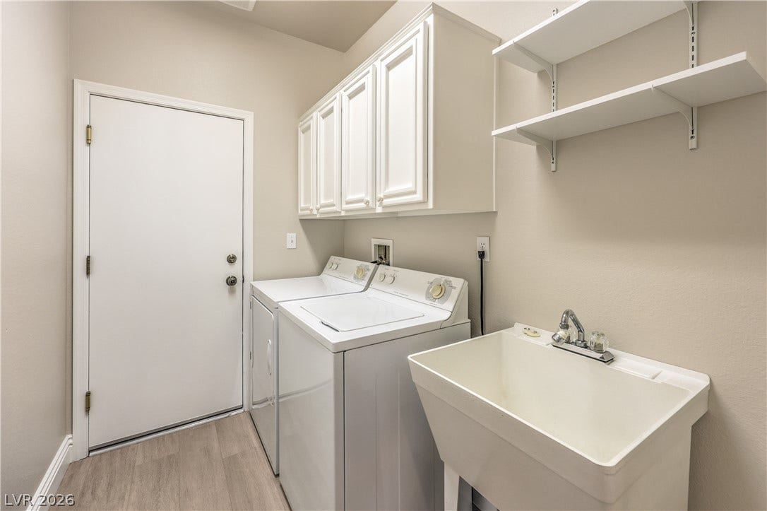 10700 Grand Cypress Avenue, Las Vegas, NV 89134 Functional laundry facilities feature overhead cabinetry, open shelving, and a utility sink.