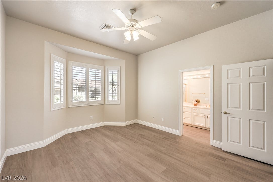 10700 Grand Cypress Avenue, Las Vegas, NV 89134 Smooth wood floors and elegant bay windows highlight this spacious primary bedroom retreat.