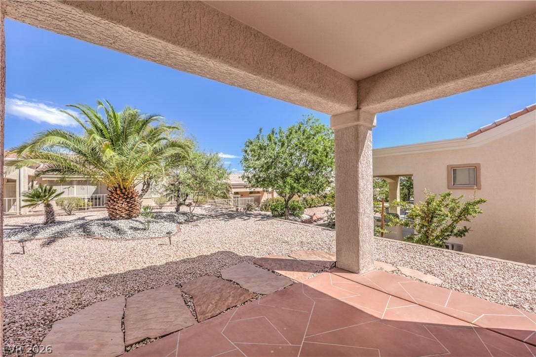 10700 Grand Cypress Avenue, Las Vegas, NV 89134 Shaded flagstone tiling frames a low-maintenance desert landscape under clear blue skies.