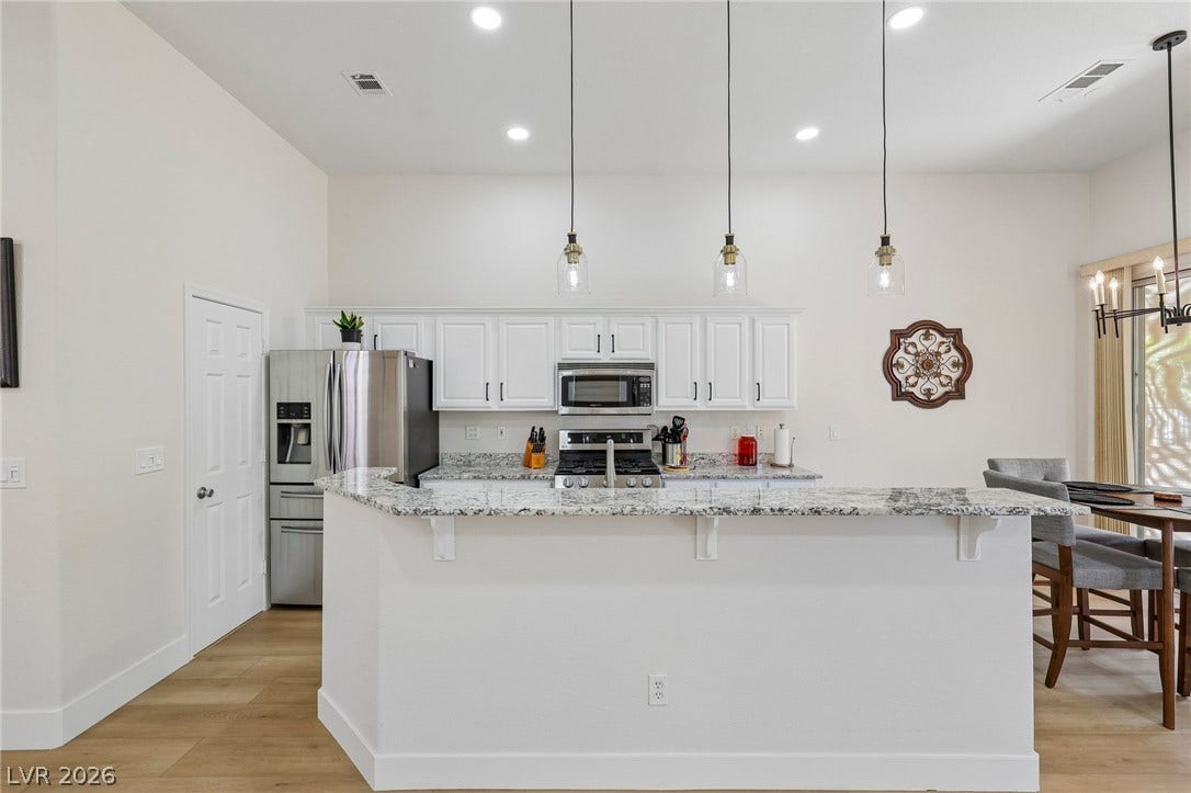 3027 Panorama Ridge Drive, Henderson, NV 89052 Polished granite countertops and classic white cabinetry define this open culinary space.