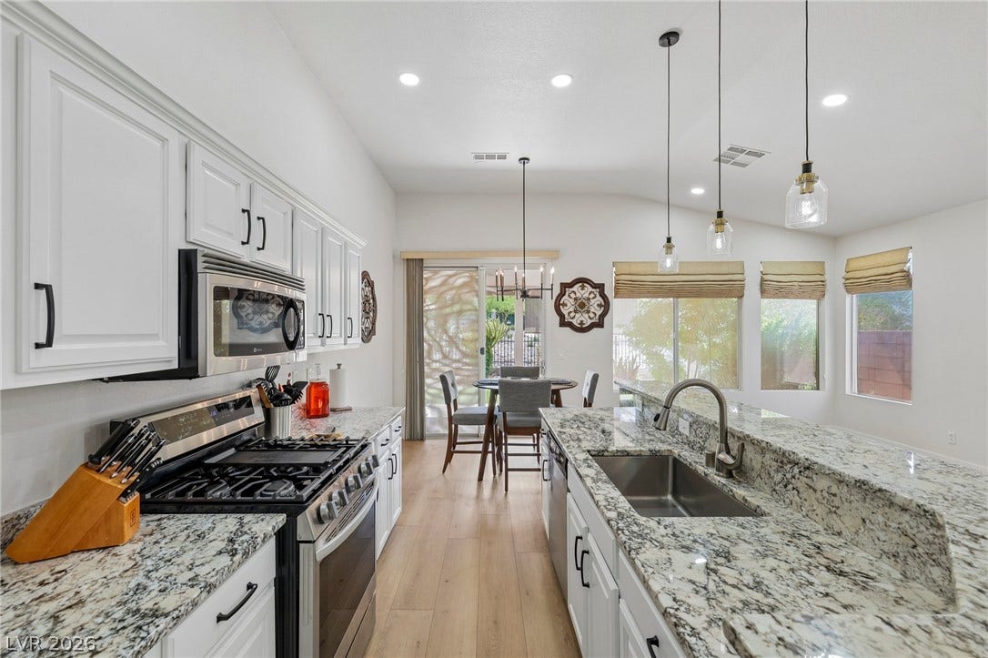 3027 Panorama Ridge Drive, Henderson, NV 89052 Gleaming granite countertops pair beautifully with light wood-like flooring in this bright kitchen.