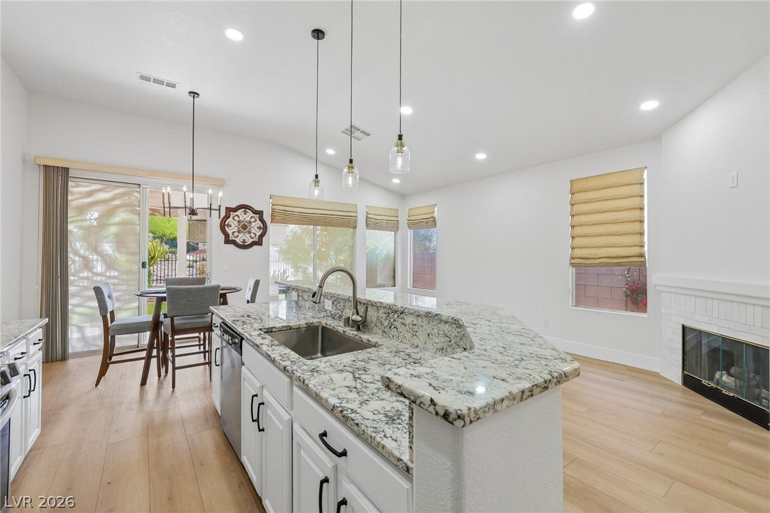3027 Panorama Ridge Drive, Henderson, NV 89052 An open kitchen featuring natural wood-look floors, granite-topped counters, and a cozy fireplace nearby.