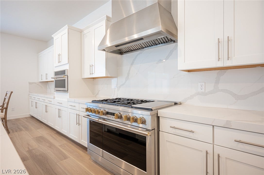 3904 Aiden Creek Avenue, North Las Vegas, NV 89031 Sleek modern cabinetry and stone backsplashes frame a professional-grade gas range.