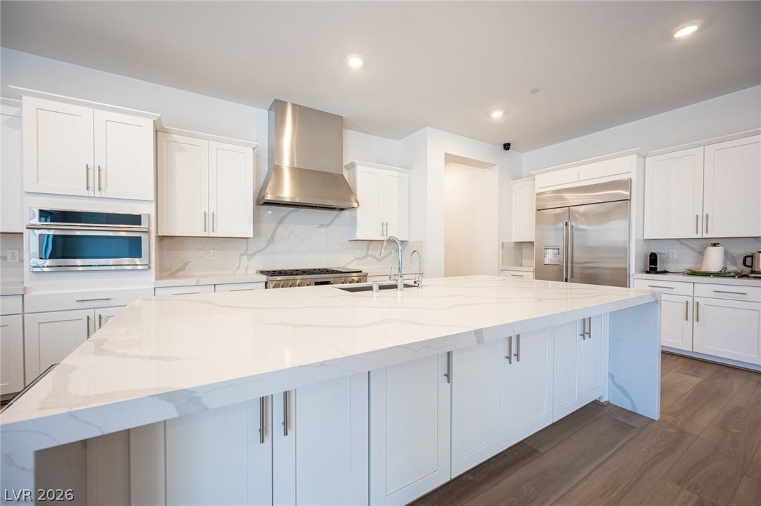 3904 Aiden Creek Avenue, North Las Vegas, NV 89031 Gleaming stone countertops and stainless steel appliances anchor this light-filled modern kitchen.
