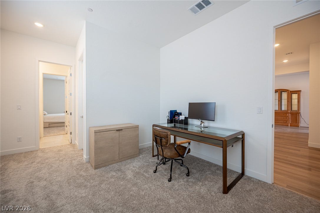 3904 Aiden Creek Avenue, North Las Vegas, NV 89031 An open office workspace features soft carpeting, recessed lighting, and smooth plaster walls.