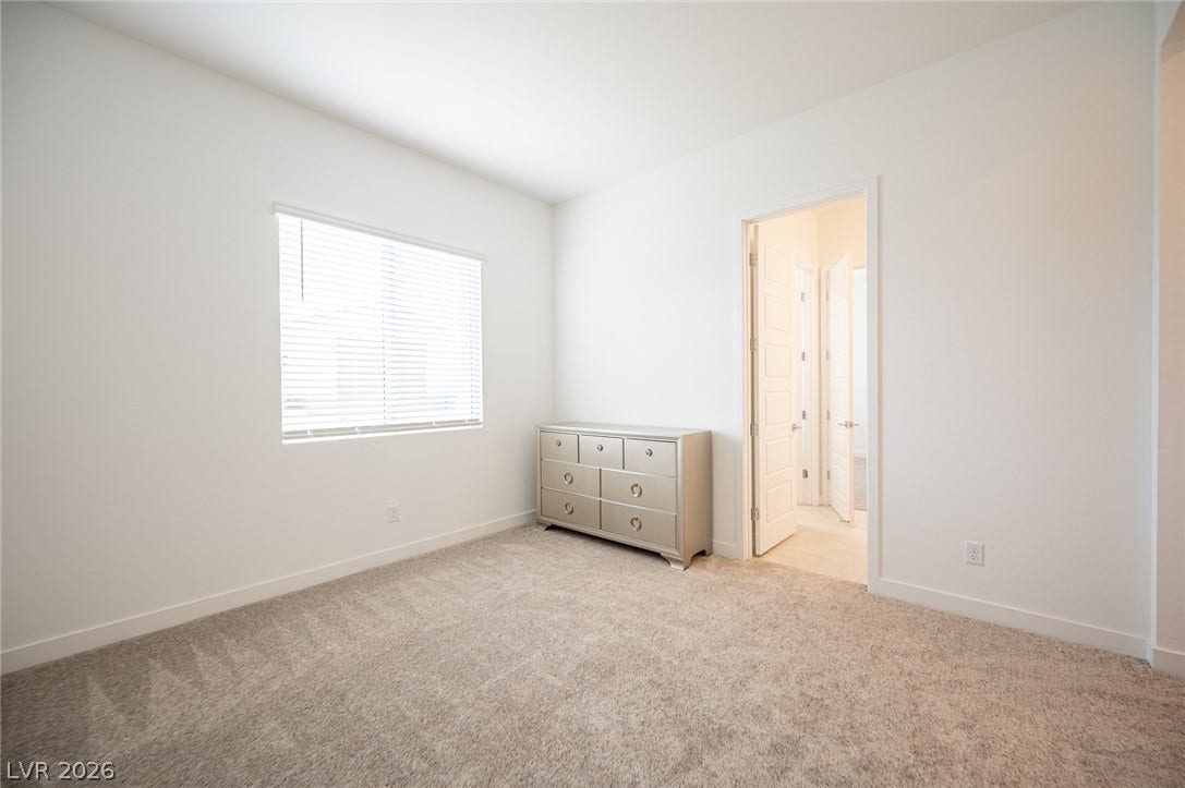 3904 Aiden Creek Avenue, North Las Vegas, NV 89031 Plush carpeting and clean white walls create a serene and versatile neutral bedroom space.