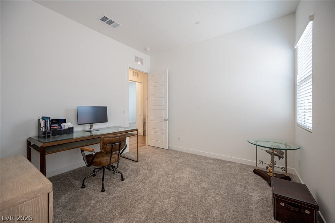 3904 Aiden Creek Avenue, North Las Vegas, NV 89031 A quiet home office features wall-to-wall carpeting and a tall window providing natural light.