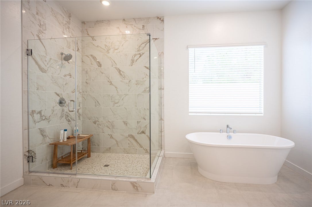 3904 Aiden Creek Avenue, North Las Vegas, NV 89031 Elegant tile work surrounds a glass-enclosed shower next to a freestanding soaking tub.