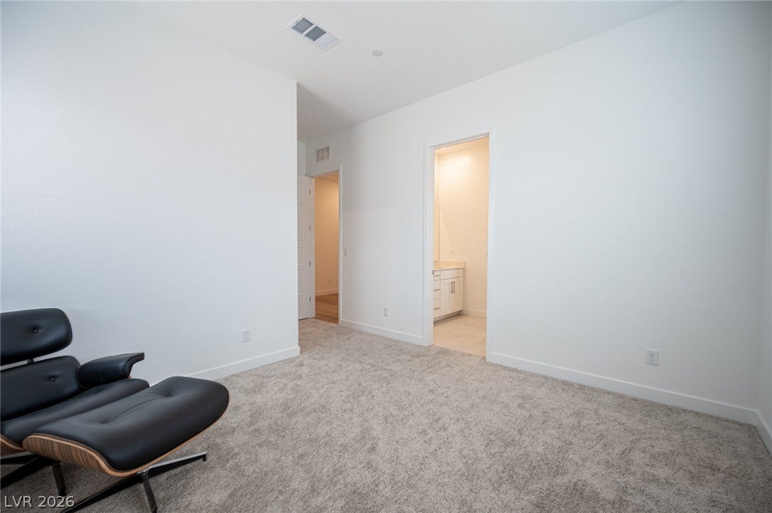 3904 Aiden Creek Avenue, North Las Vegas, NV 89031 Plush carpeting and crisp neutral walls define this comfortable bedroom featuring an attached private bathroom.
