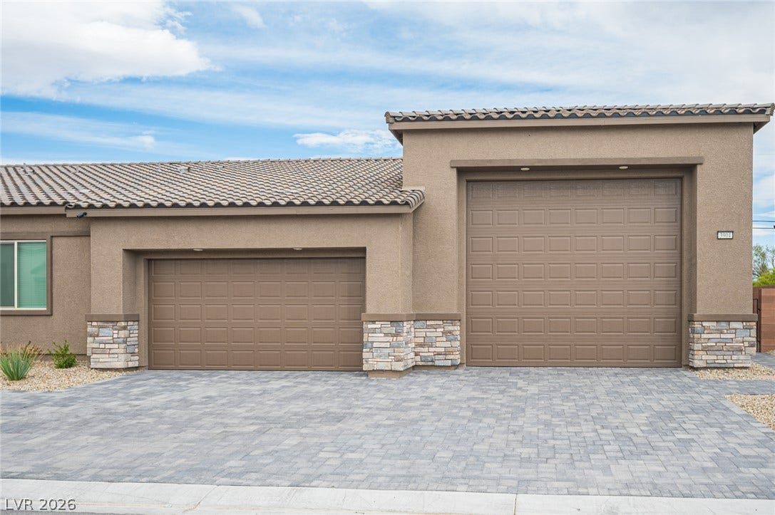 3904 Aiden Creek Avenue, North Las Vegas, NV 89031 An expansive paver driveway leads to a stucco exterior complemented by stone veneer accents.
