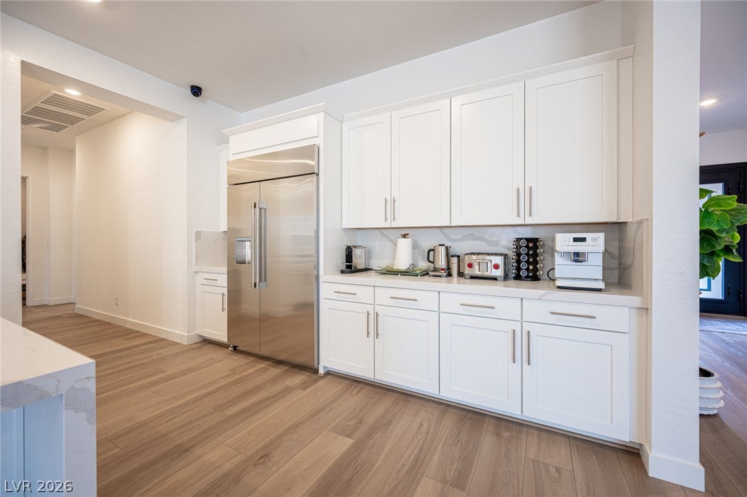 3904 Aiden Creek Avenue, North Las Vegas, NV 89031 Sleek cabinetry and stone countertops complement the modern wood-plank flooring in this kitchen space.