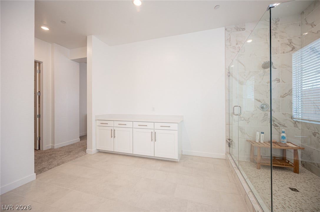 3904 Aiden Creek Avenue, North Las Vegas, NV 89031 An elegant glass-enclosed shower showcases beautiful marble-patterned tile and a spacious stone-topped vanity.