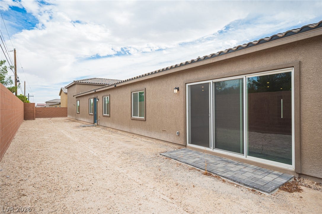 3904 Aiden Creek Avenue, North Las Vegas, NV 89031 A long stucco exterior features sliding glass doors opening to a paved patio area.