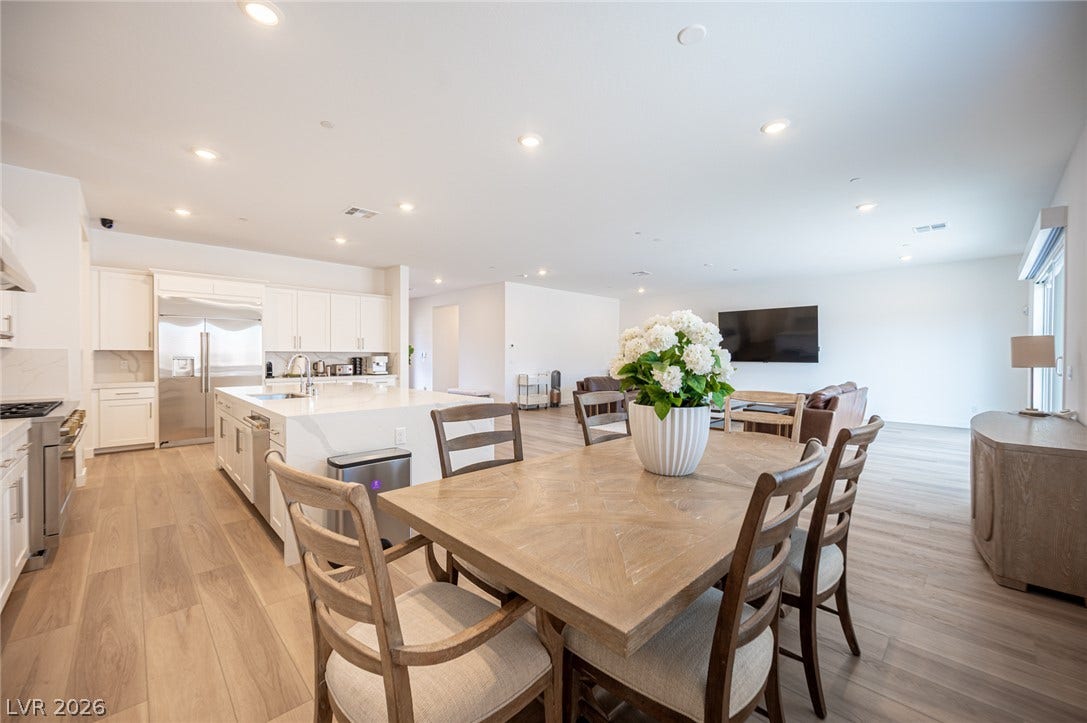3904 Aiden Creek Avenue, North Las Vegas, NV 89031 Polished LVP flooring spans across a spacious, seamlessly integrated kitchen and living layout.