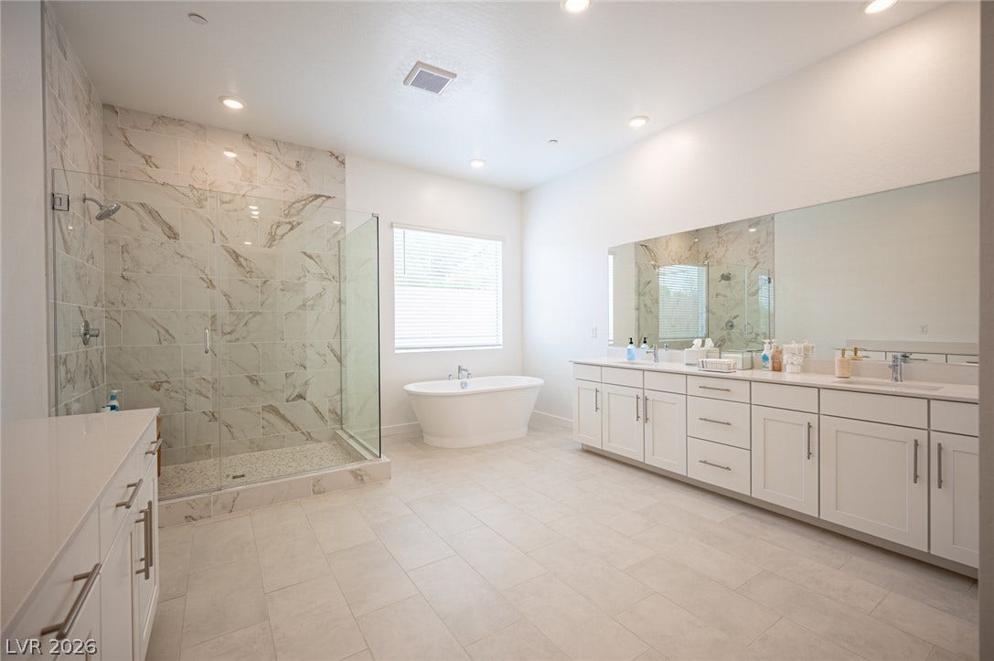 3904 Aiden Creek Avenue, North Las Vegas, NV 89031 Polished tile floors and an expansive double vanity elevate this modern primary bath.