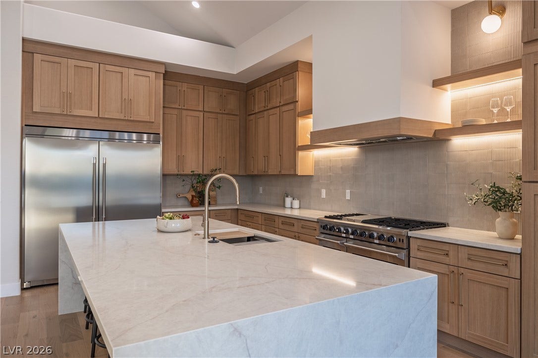 8800 Lusso Court, Las Vegas, NV 89134 Kitchen with light stone counters, high quality appliances, backsplash, a center island with sink, and light wood finished floors