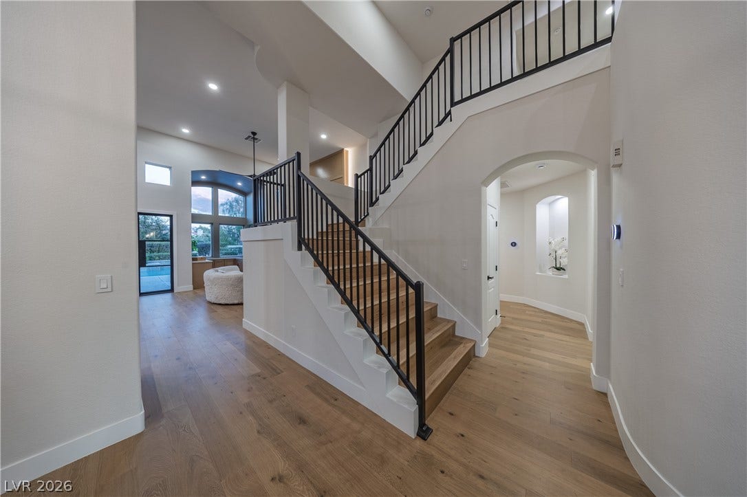8800 Lusso Court, Las Vegas, NV 89134 Stairs with a high ceiling, arched walkways, and wood-type flooring