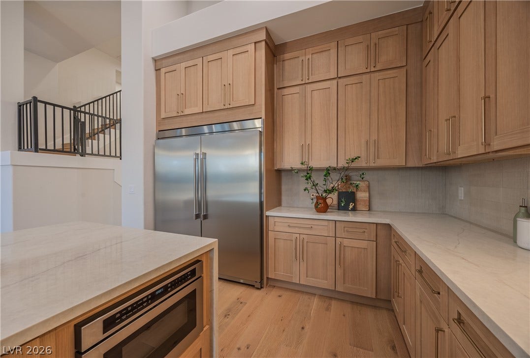8800 Lusso Court, Las Vegas, NV 89134 Kitchen featuring built in appliances, light wood finished floors, decorative backsplash, light stone countertops, and light wood finish cabinetry