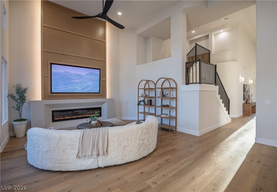 8800 Lusso Court, Las Vegas, NV 89134 Living area with hardwood / wood-style flooring, a high ceiling, a glass covered fireplace, a ceiling fan, and recessed lighting