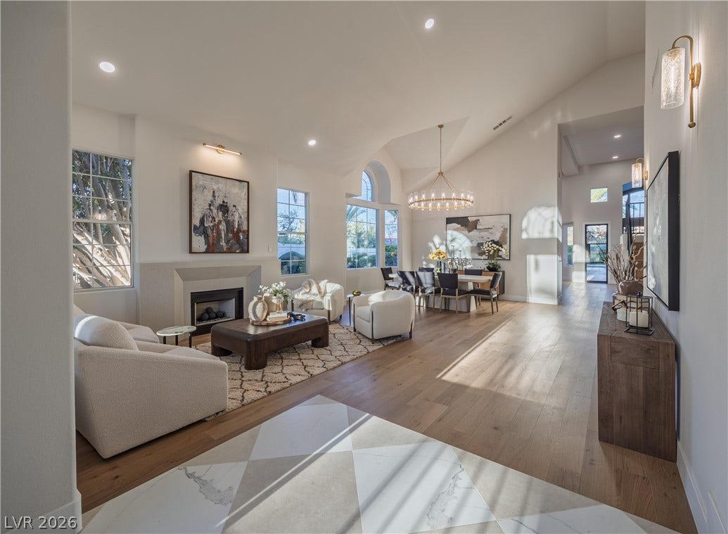 8800 Lusso Court, Las Vegas, NV 89134 Living area with light wood-type flooring, vaulted ceiling, a fireplace, and plenty of natural light