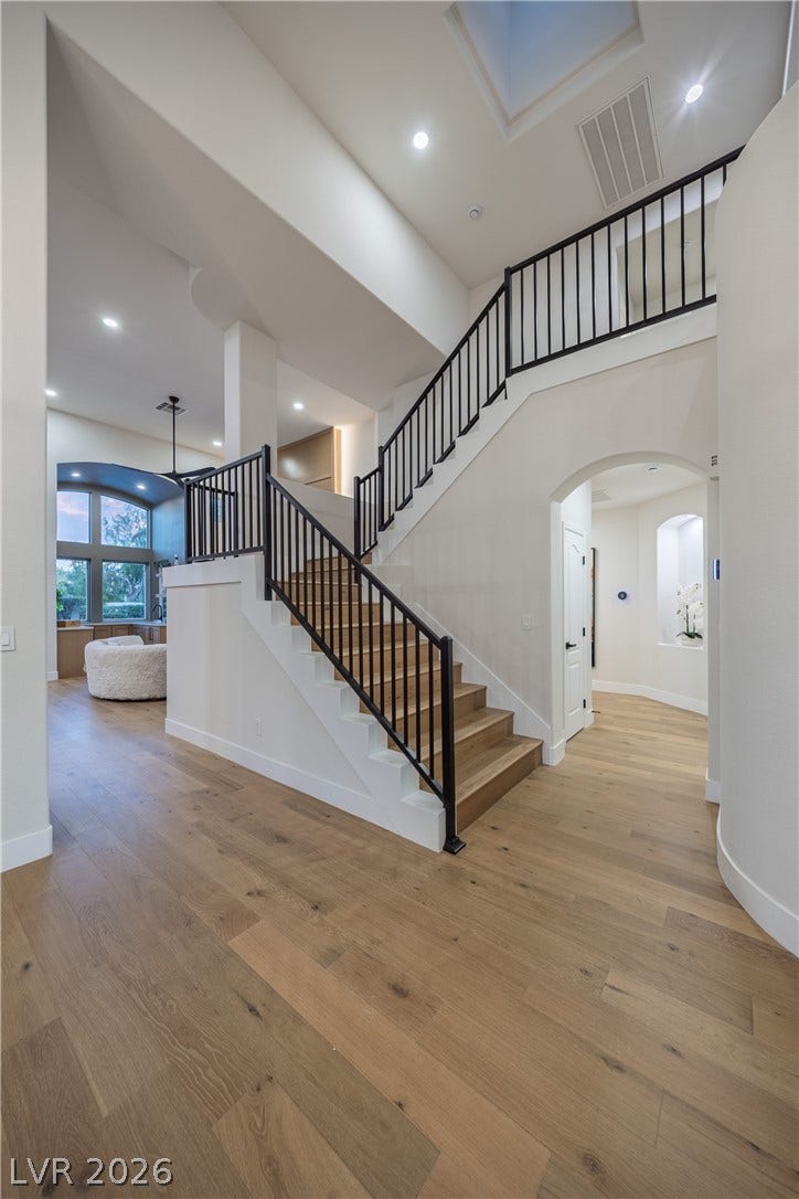 8800 Lusso Court, Las Vegas, NV 89134 Stairs with arched walkways, hardwood / wood-style flooring, a high ceiling, and recessed lighting