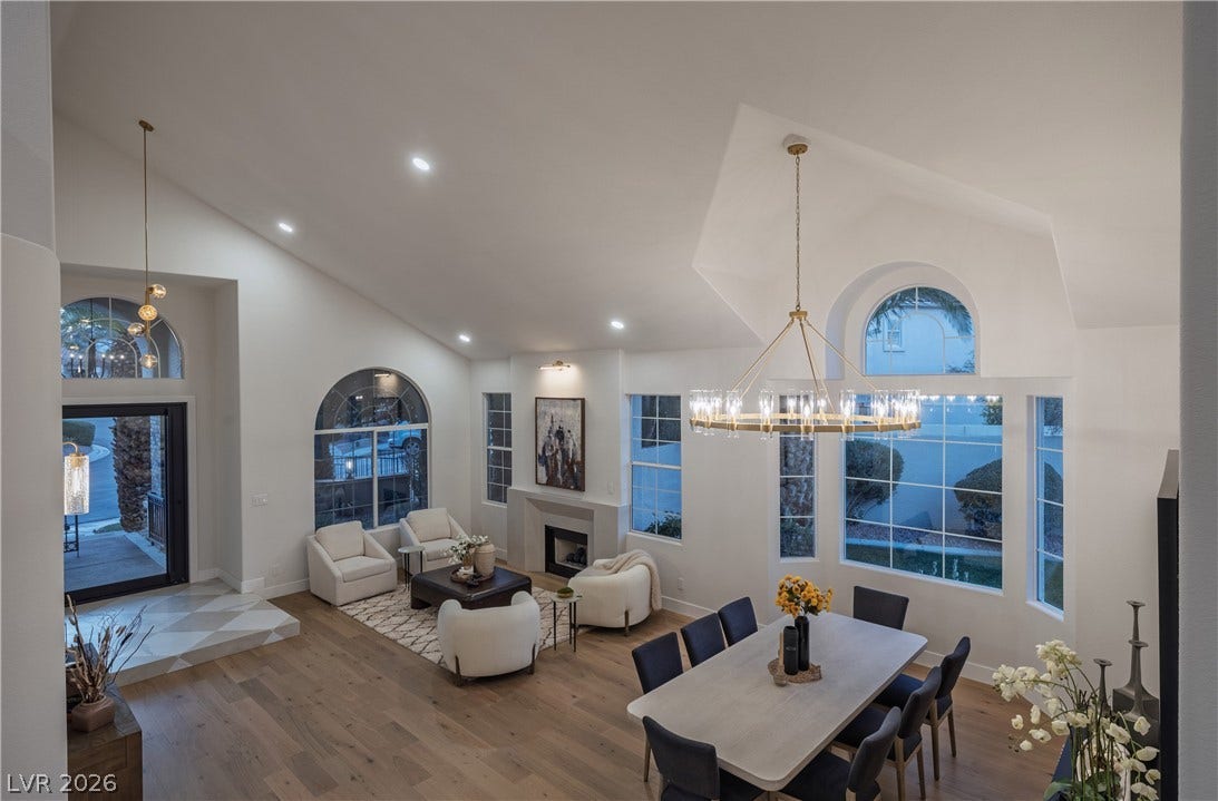 8800 Lusso Court, Las Vegas, NV 89134 Dining space featuring a glass covered fireplace, lofted ceiling, a chandelier, wood finished floors, and plenty of natural light