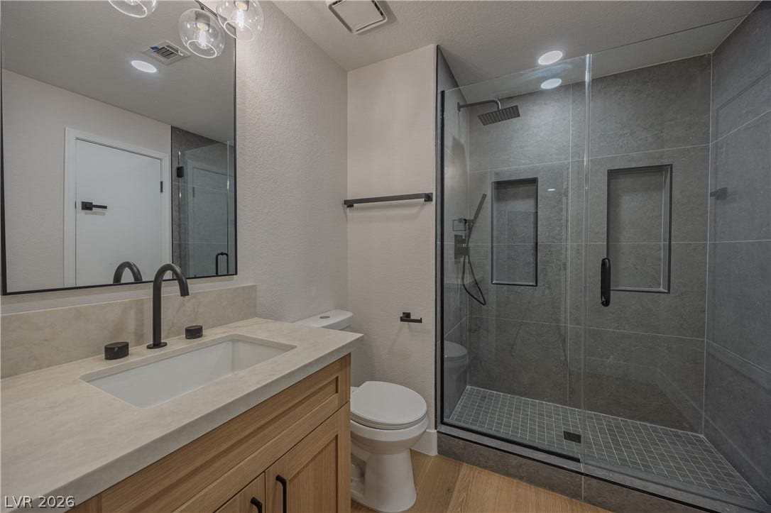 8800 Lusso Court, Las Vegas, NV 89134 Bathroom featuring vanity, a stall shower, light wood-style floors, and a textured wall
