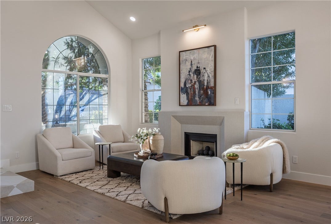 8800 Lusso Court, Las Vegas, NV 89134 Living area featuring a fireplace, hardwood / wood-style floors, vaulted ceiling, and healthy amount of natural light