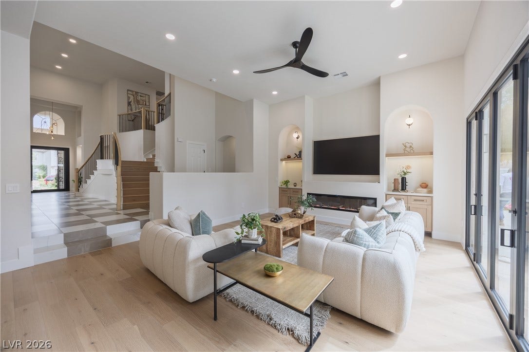 Living room featuring built in features, a ceiling fan, a high ceiling, recessed lighting, and light wood-type flooring
