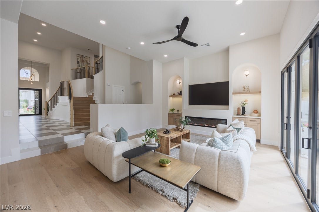 Living room with built in features, ceiling fan, recessed lighting, a high ceiling, and light wood-style flooring