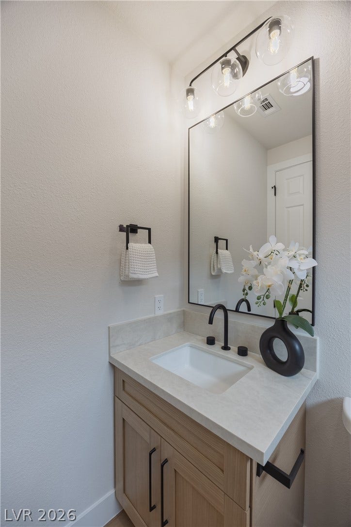 Bathroom with vanity and a textured wall