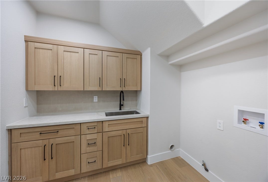 Laundry room with hookup for a gas dryer, light wood finished floors, hookup for a washing machine, cabinet space, and vaulted ceiling