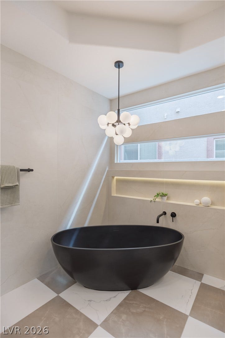 Full bath featuring a soaking tub and a chandelier