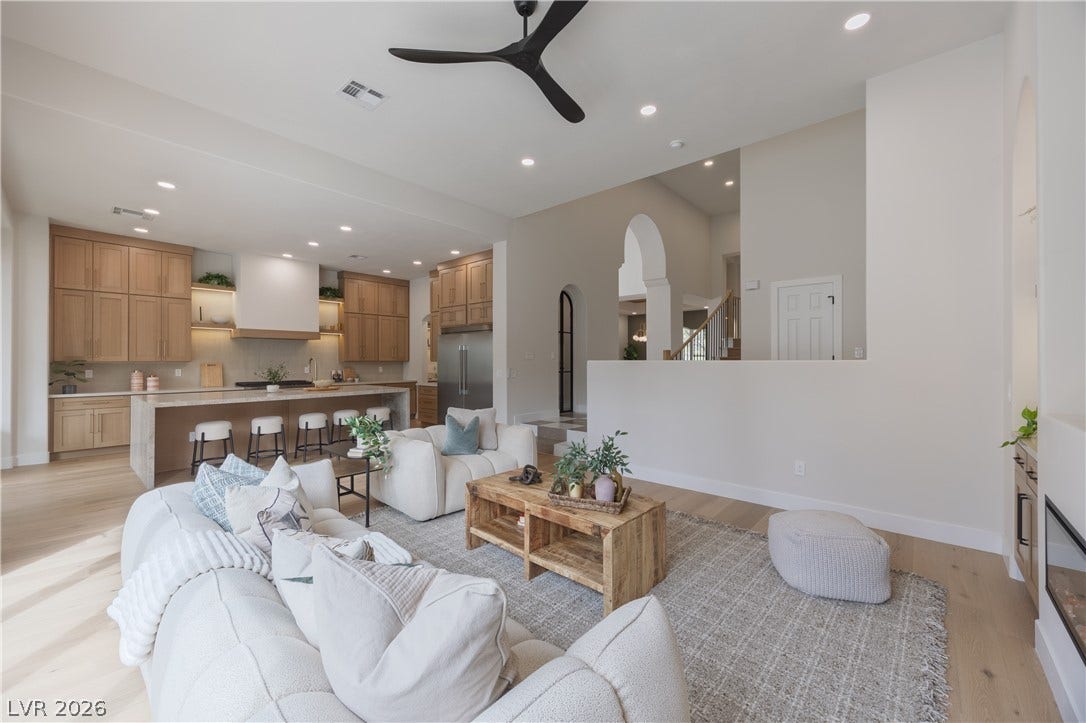 Living room with light wood finished floors, ceiling fan, recessed lighting, and arched walkways