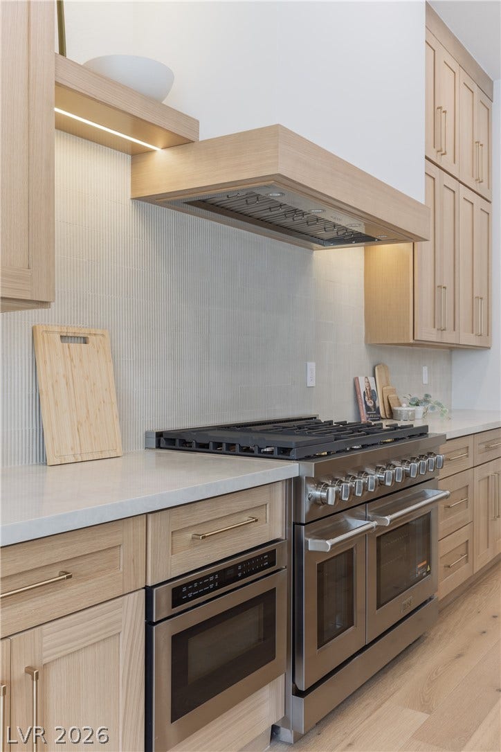 Kitchen featuring light wood finish cabinetry, stainless steel appliances, light wood-type flooring, and light stone counters