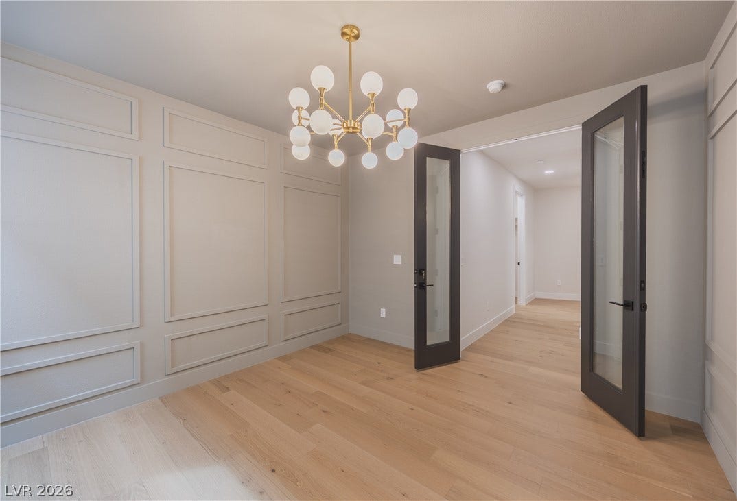Unfurnished dining area with suspended lighting, light wood-style flooring, and a decorative wall