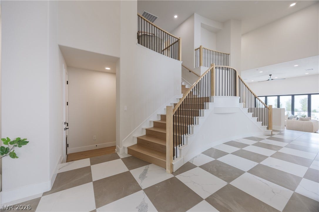 Stairway with a high ceiling, recessed lighting, and a ceiling fan