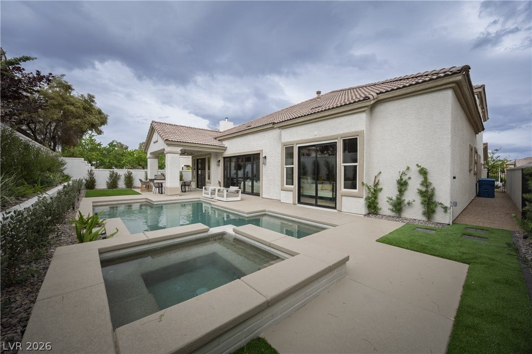Back of property with an in-ground hot tub, a patio, a fenced backyard, stucco siding, and a tile roof