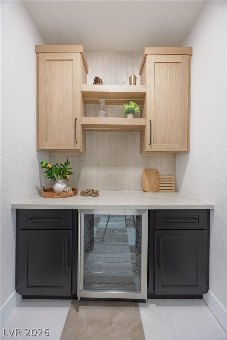 Bar featuring beverage cooler, dual tone cabinets, backsplash, light stone countertops, and open shelves